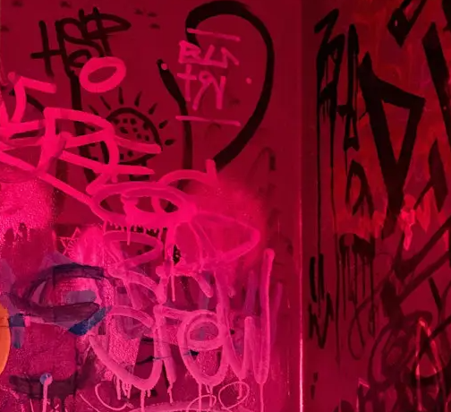A wall in pink light with graffiti