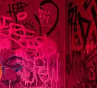A wall in pink light with graffiti