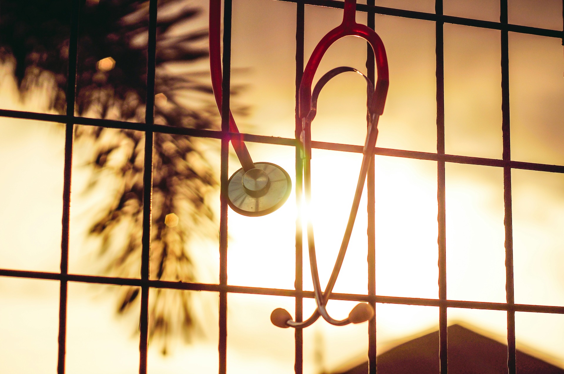 A stethoscope hanging on a window bar in a sunset.