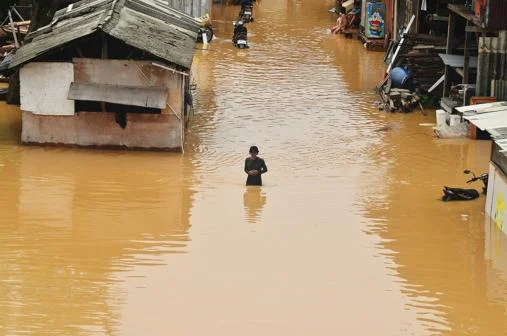 A person waist-deep in flood water.
