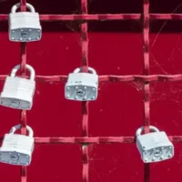 A red metal grid fence with padlocks attached to it