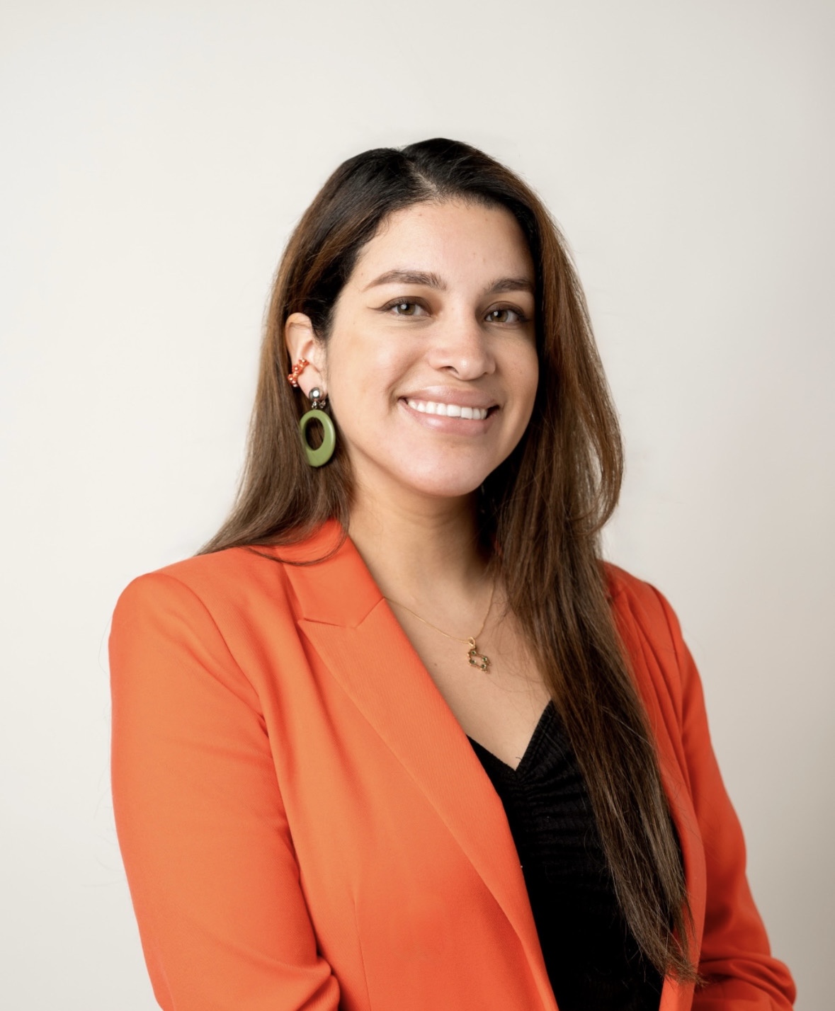 Selena Chávez is facing the camera and smiling. She is wearing an orange jacket.