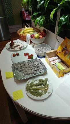 Differents foods on a table, including fruits, chocolate, and a matcha-flavoured cake.