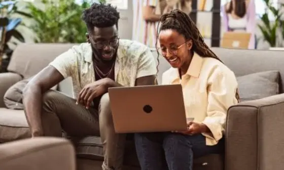 A girl and a guy siting and reading from a laptop.