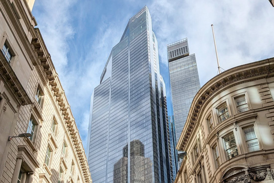 A sky scraper rises between two old buildings in the City of London