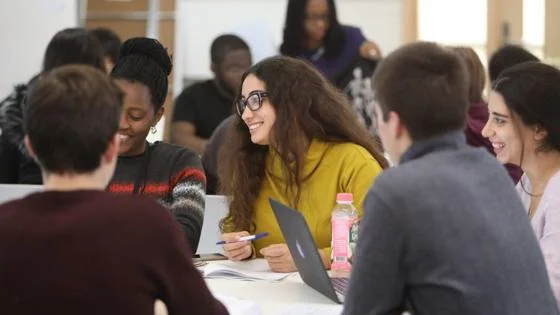Students in a classroom smiling and writing