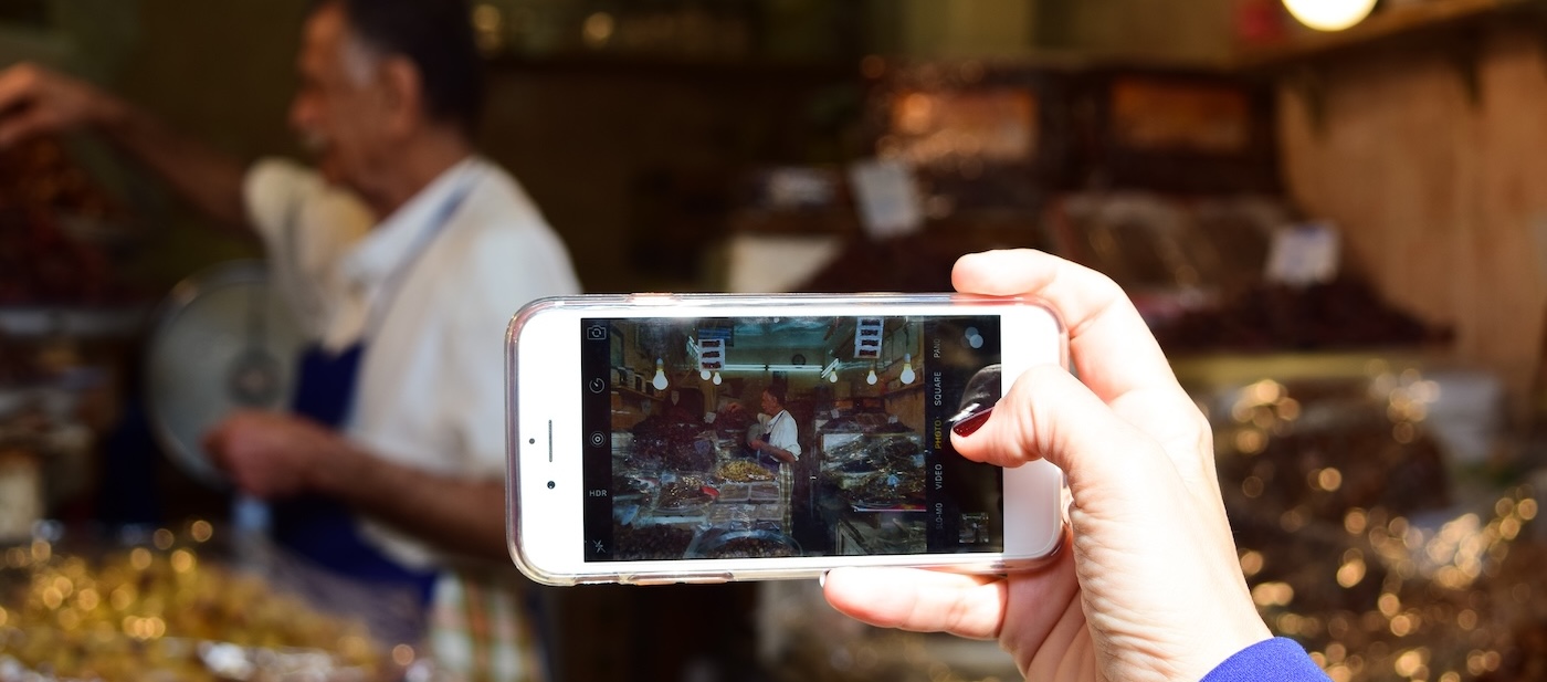 Person taking a photo of a food stall in Al Mubarakiya souk, Kuwait City. 
