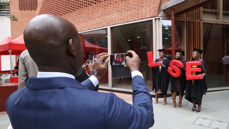 A man takes a photo of LSE graduates