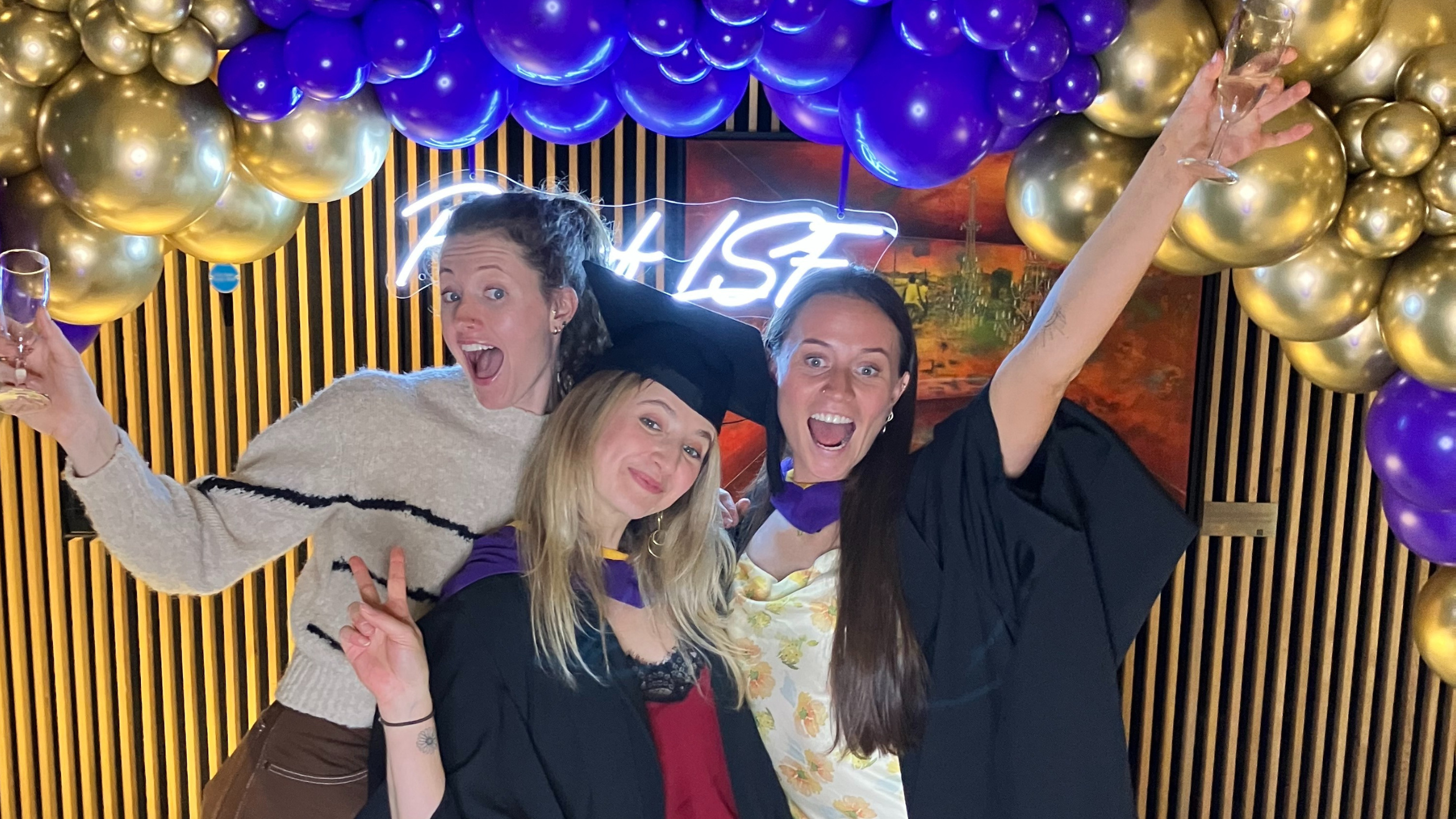 Students at Graduation posing under balloons.