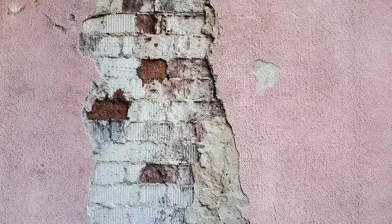 A pink wall with exposed brick
