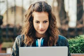Student sitting on a bench looking at a laptop
