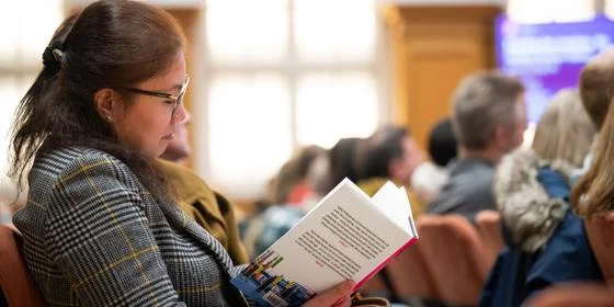 Student in a lecture theatre reading a book