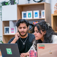 man and woman talking with two laptops in front of them