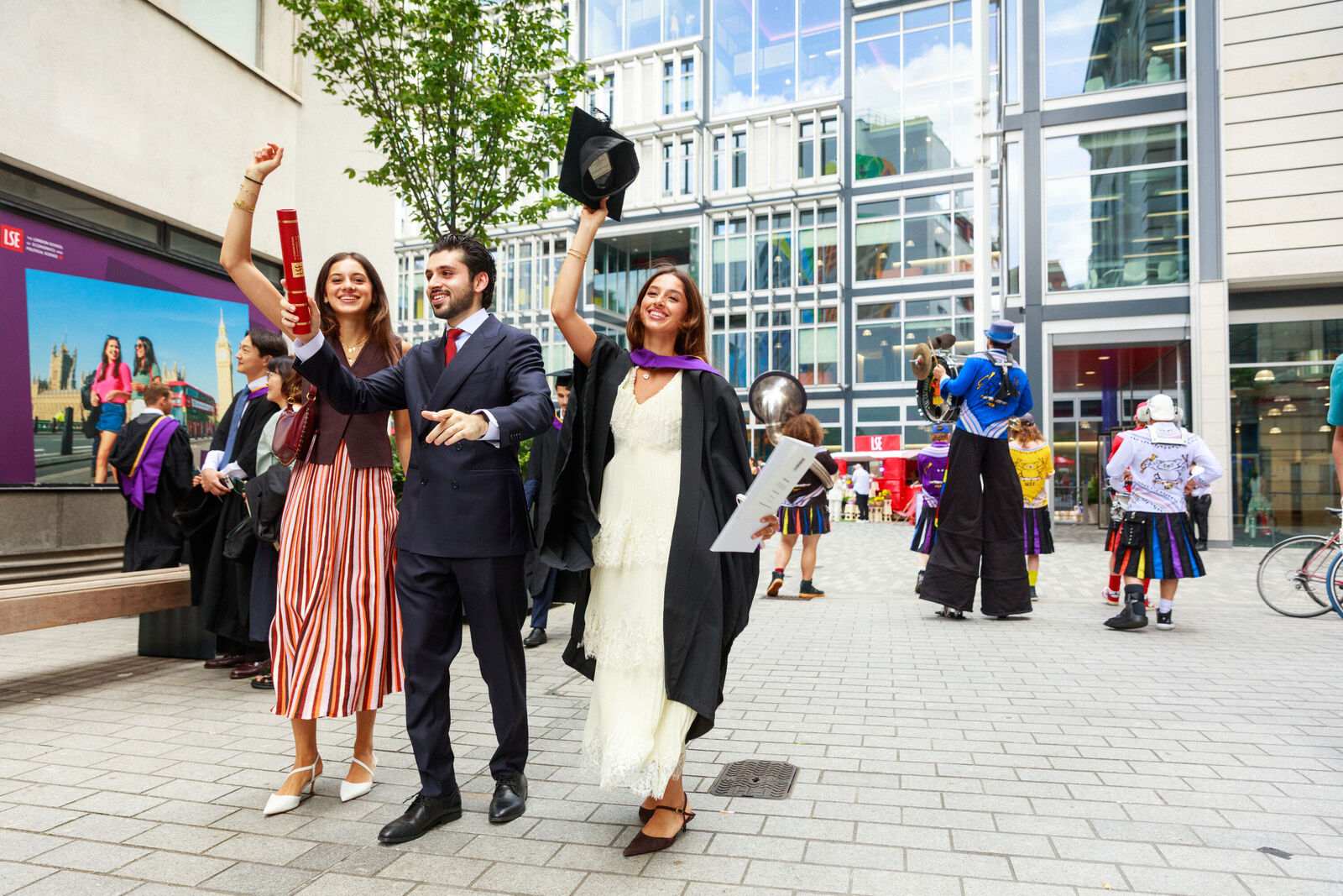A graduate and friends raising their hands and smiling