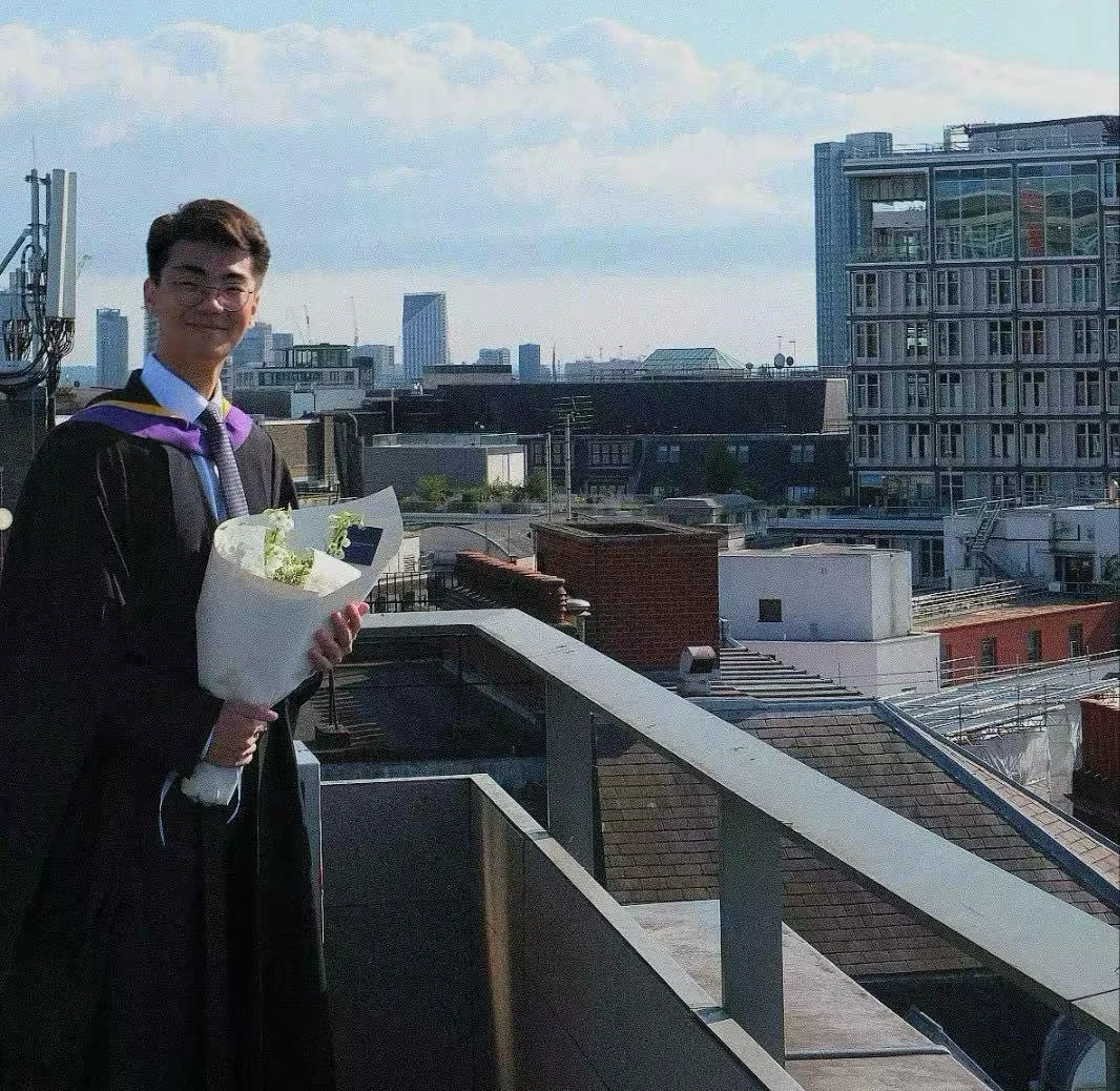 Sung Jae Harry Park is pictured in his LSE graduation gown with a bouquet of flowers and the London skyline in the background.