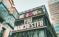 A modern building with 'We Love You Manchester' written on the side.