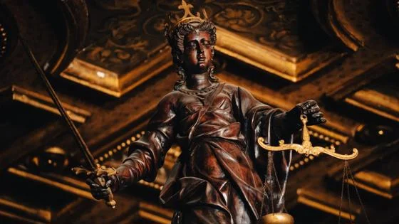 A dramatic bronze Lady Justice statue holding a sword and scales.