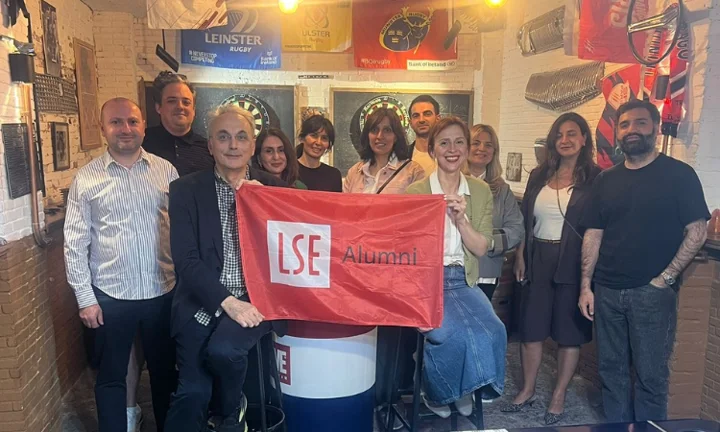 Alumni gather for a photo, proudly holding the LSE alumni flag.