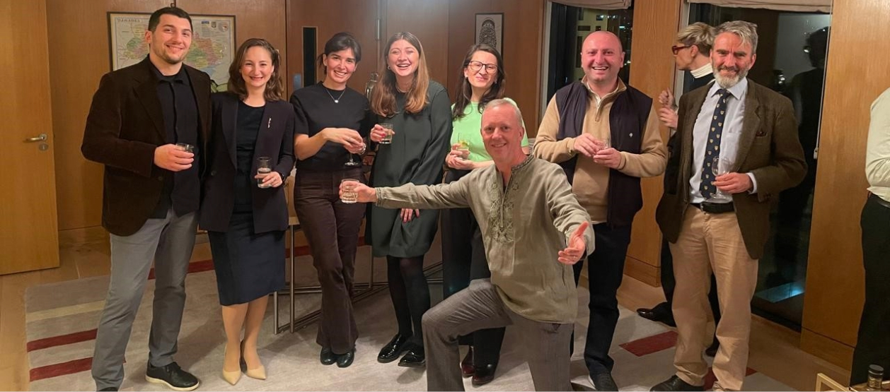 Group of alumni in Tbilisi gathered, some with drinks.