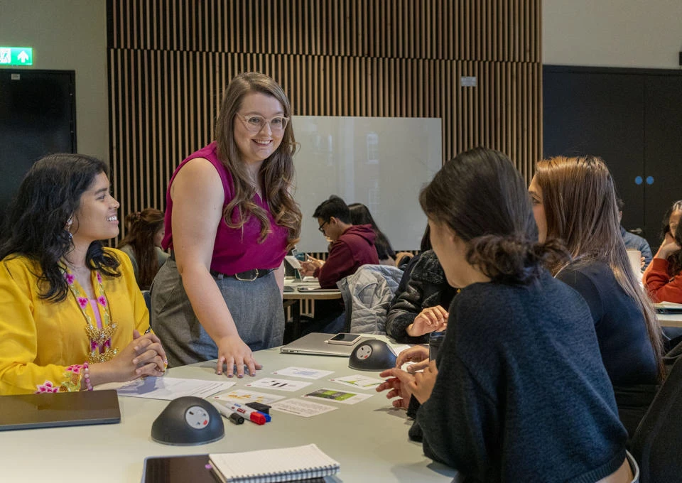 An LSE100 teacher with students in a classroom