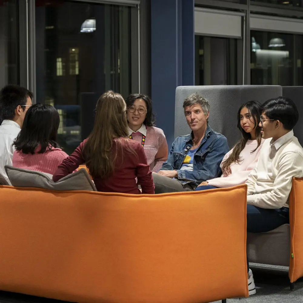 A teacher and students sitting on a sofa