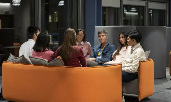 A teacher and students sitting on a sofa