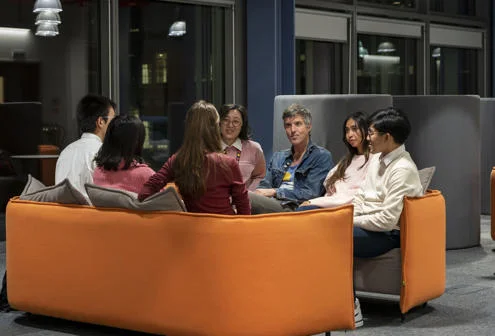 A teacher and students sitting on a sofa