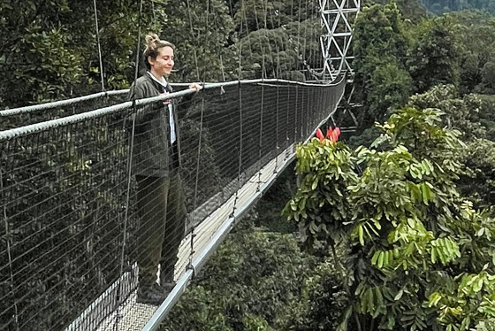 Ottavia Pesce stands on a bridge suspended over a large forest