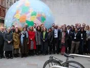Speakers from Too Much Finance conference standing in front of globe sculpture at LSE