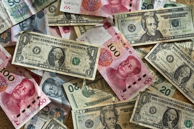 Currency Collection Featuring United States and Chinese Banknotes Spread Across A Flat Surface 
