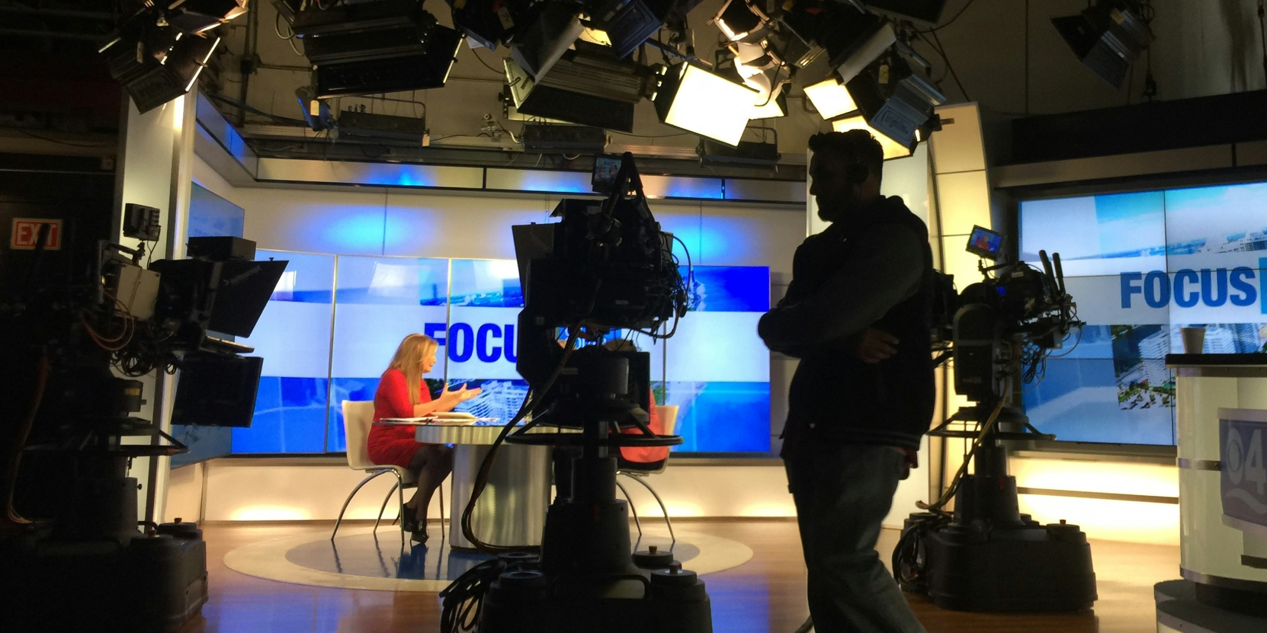 The production side of a busy TV newsroom showing cameras and a set