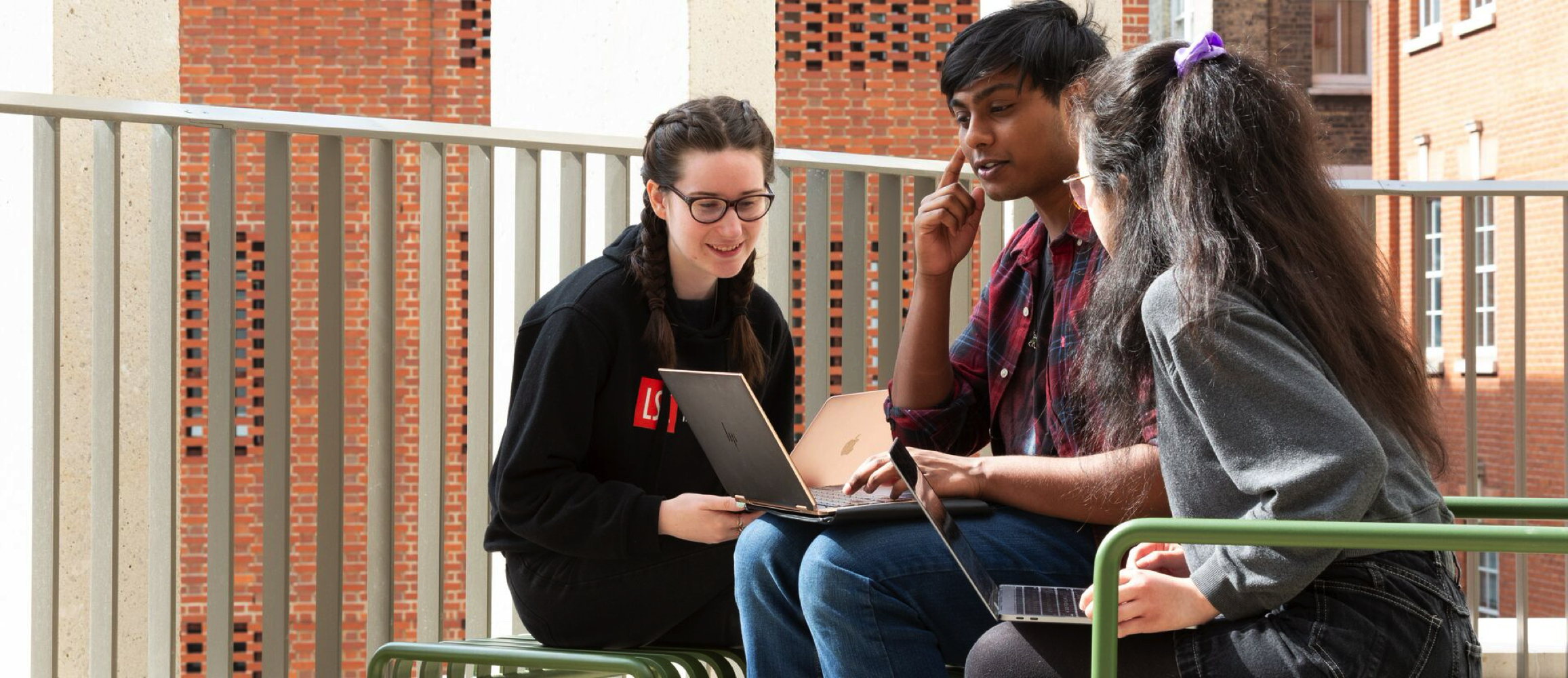 Three students looking at laptops
