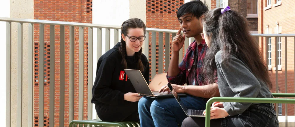 Three students looking at laptops