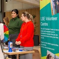 two people standing in front of a banner advertising the LSE Volunteer Centre