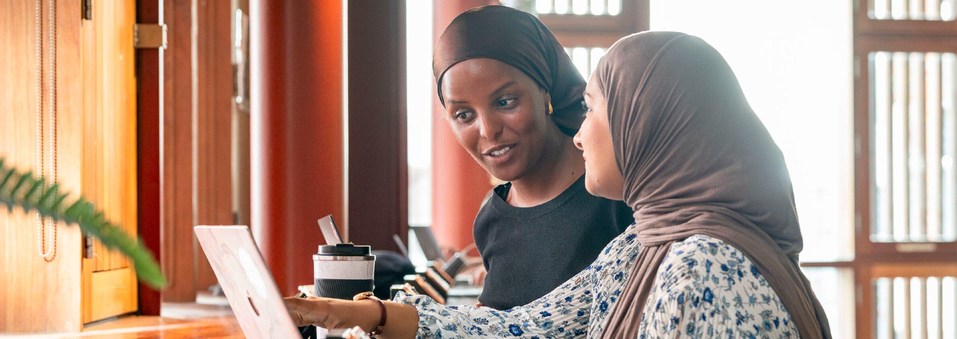 Two female students looking at laptops and chatting