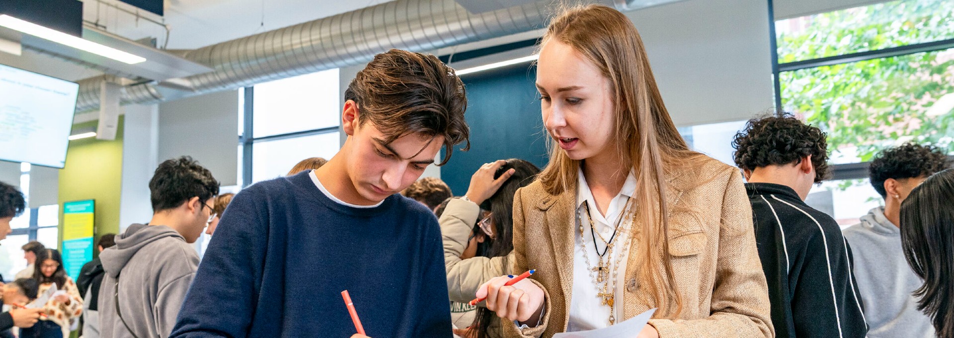 Two students at Welcome talk and take notes