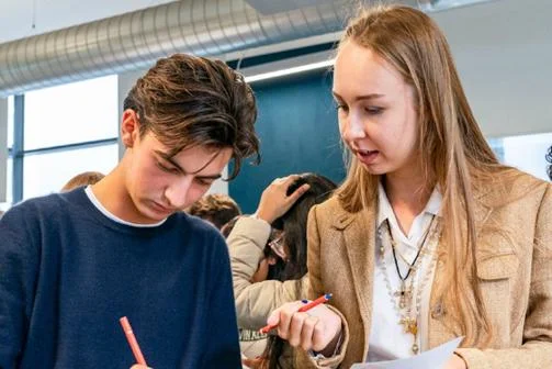 Two students at Welcome talk and take notes