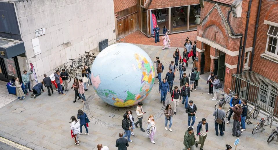 Students walk past the globe on LSE campus during Welcome