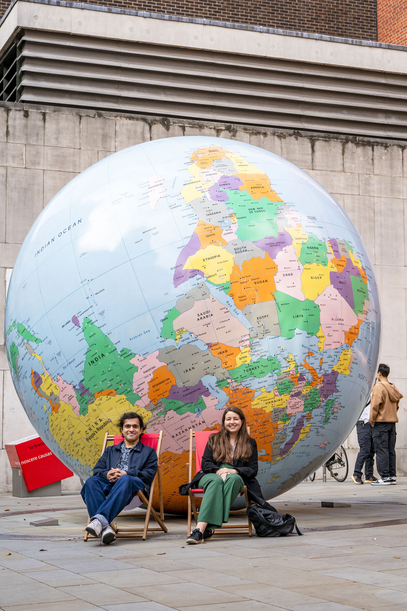 Two people sitting in front of LSE's globe in deck chairs