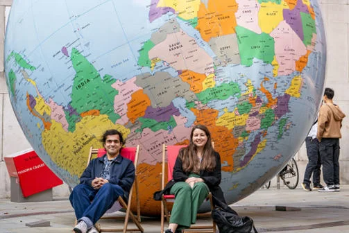 Two people sitting in front of LSE's globe in deck chairs