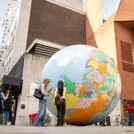 Students standing in front of "The World Turned Upside Down" sculpture by Mark Wallinger, on the LSE campus