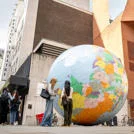 Students standing in front of "The World Turned Upside Down" sculpture by Mark Wallinger, on the LSE campus