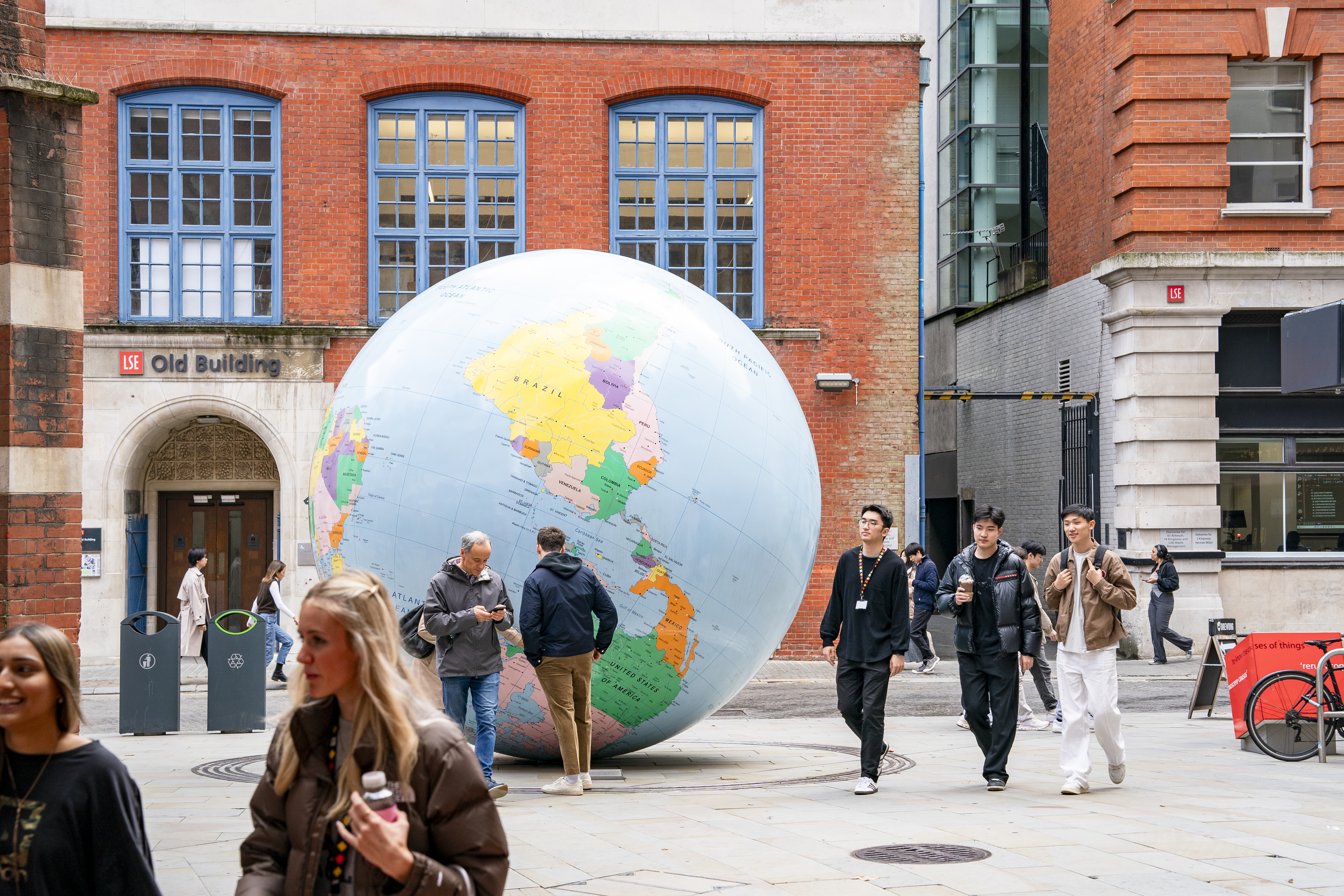 Students walking past a large globe on campus