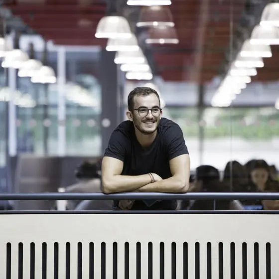 Smiling man leaning on balcony of academic building