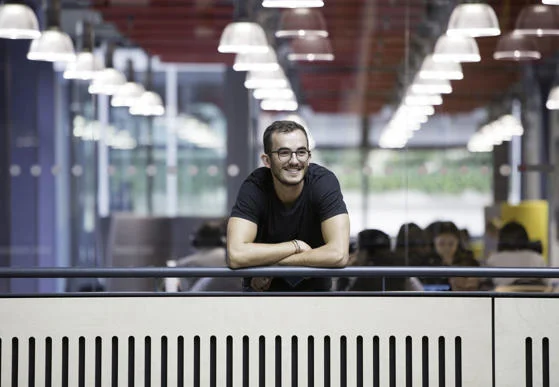 Smiling man leaning on balcony of academic building