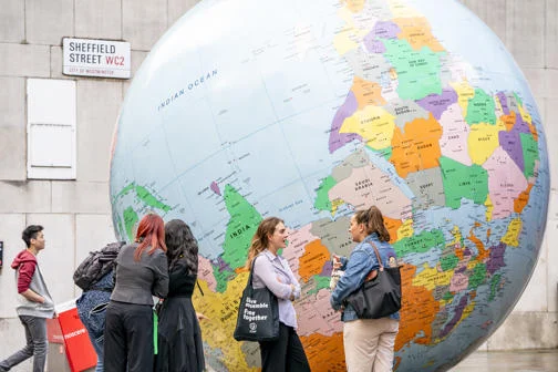 Students standing by "The World Turned Upside Down" sculpture by Mark Wallinger