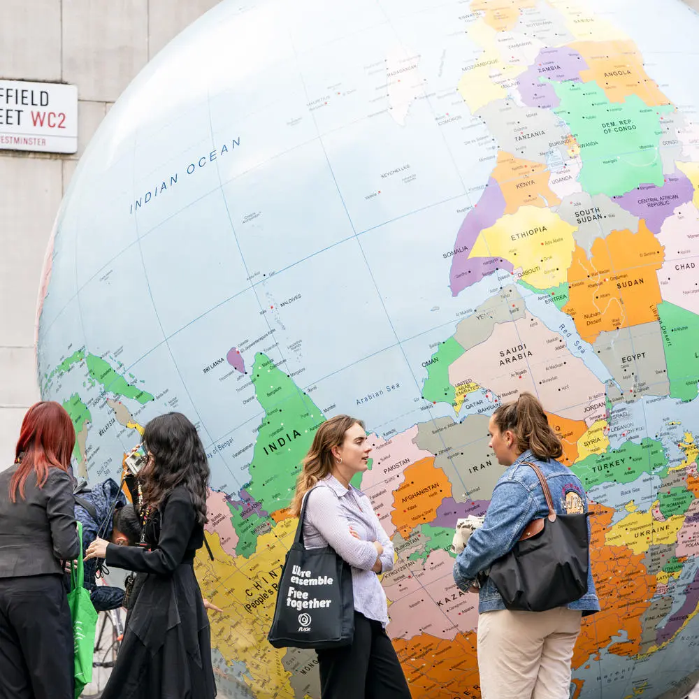 A group of people next to the LSE globe