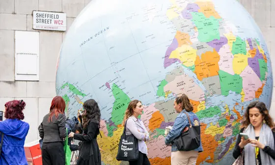 A group of people next to the LSE globe