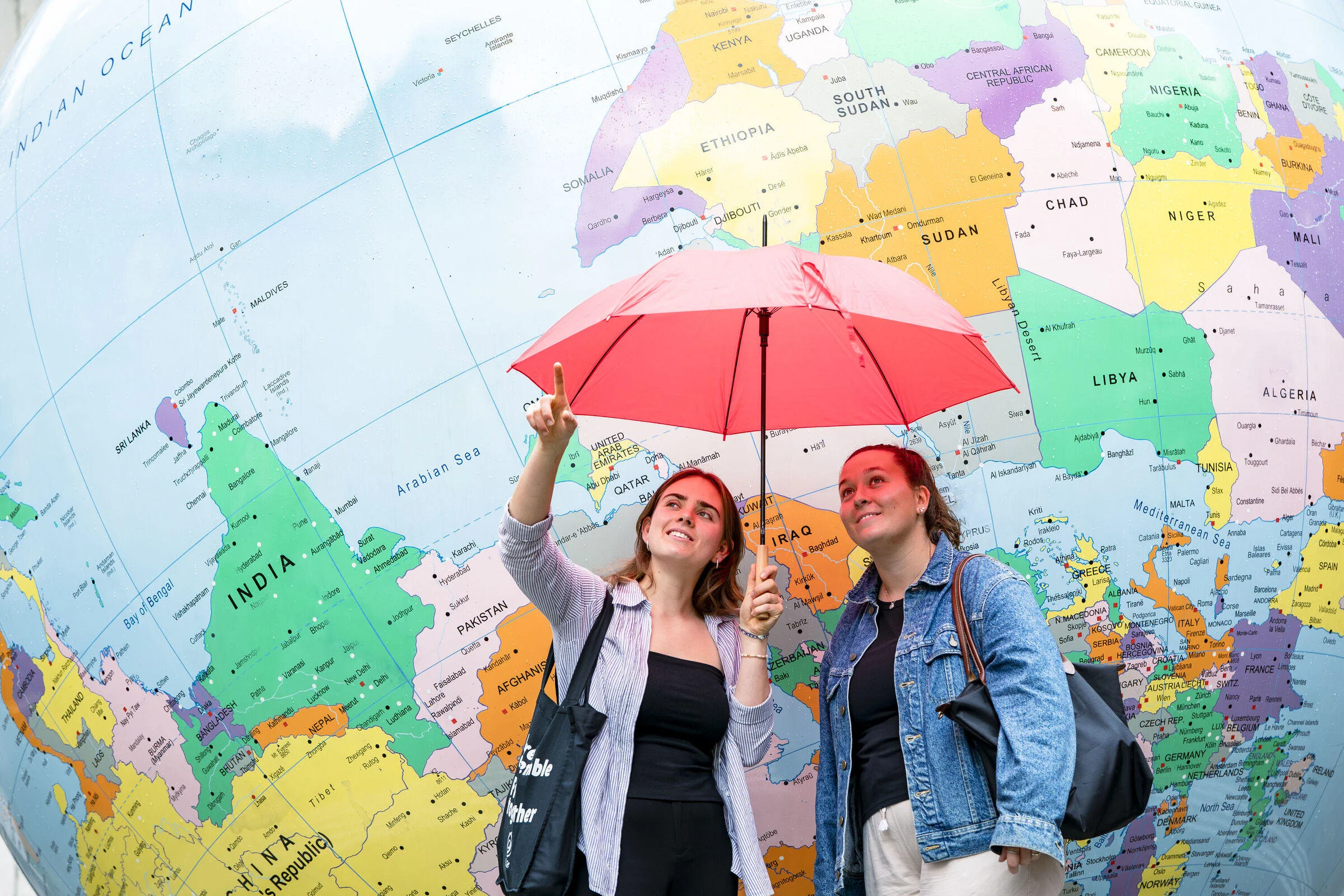 two girls stranding in front of globe