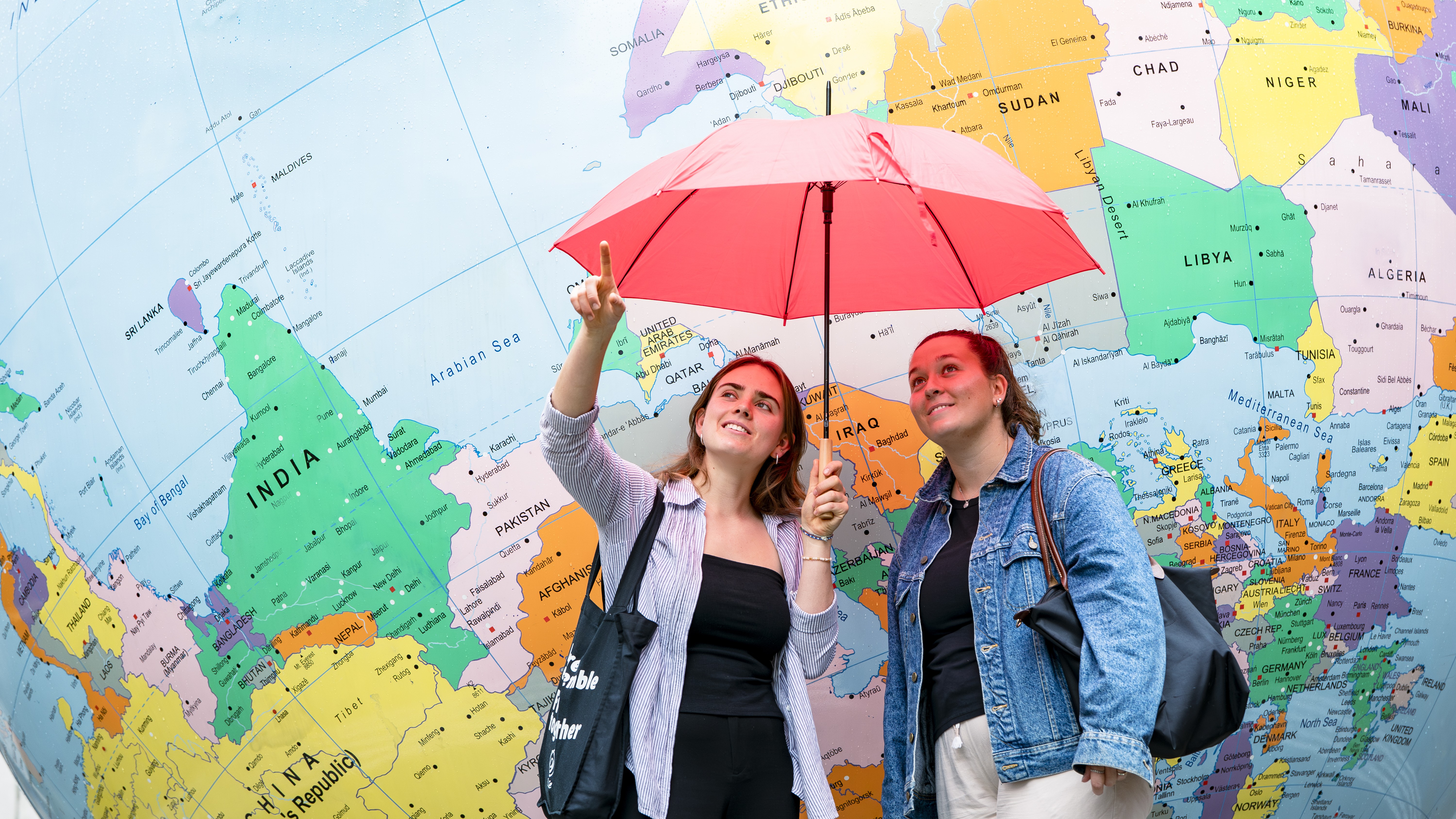 Students with an umbrella in front of the globe